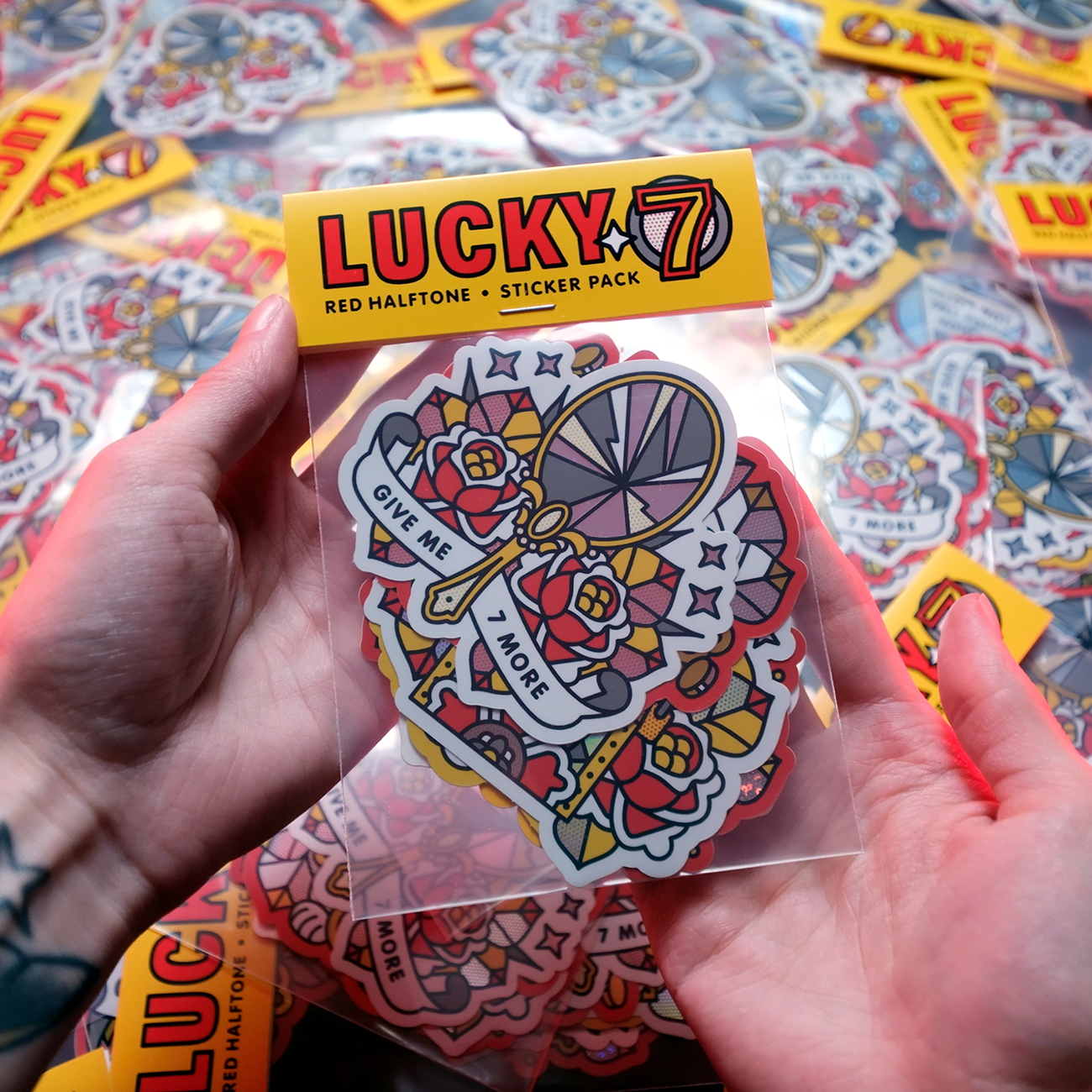 Hände halten ein buntes Sticker Pack mit der Aufschrift "Lucky 7," mit holografischen, glitzernden und spiegelnden Aufklebern.