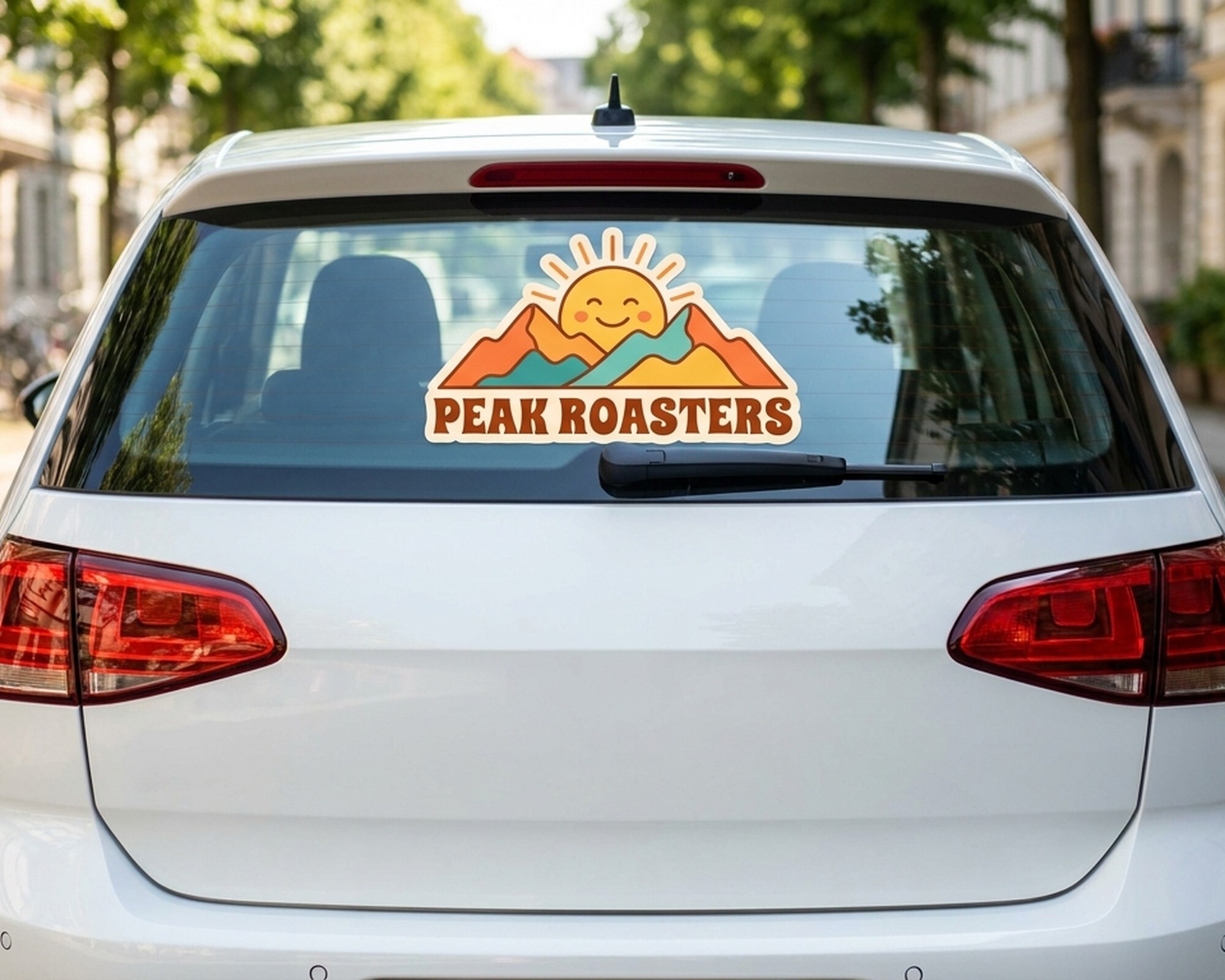 Eigenes Freiform-Decal mit Sonne-und-Berge-Logo und dem Schriftzug „Peak Roasters“ auf der Heckscheibe eines Autos