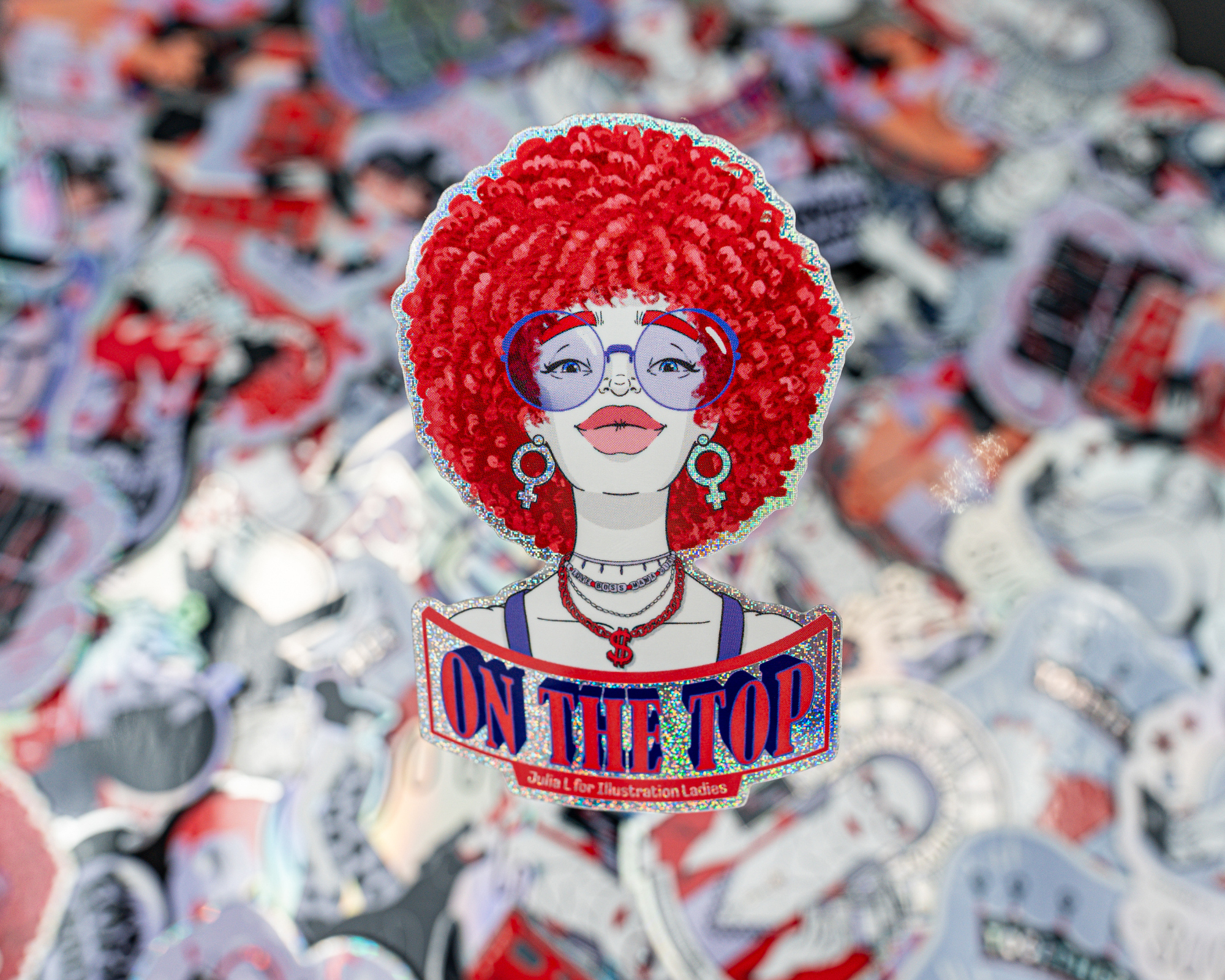 Aufkleber einer stilisierten Frau mit rotem Afro, Brille und Schmuck. Darunter steht "On the Top". Hintergrund aus weiteren bunten Aufklebern.